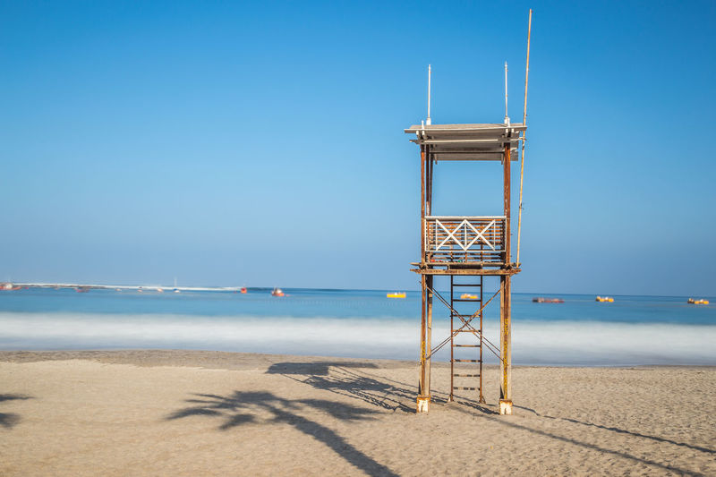 Lookout tower at beach against clear blue sky