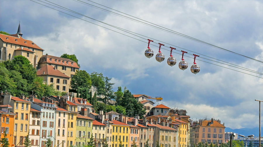Low angle view of overhead cable cars in city against sky