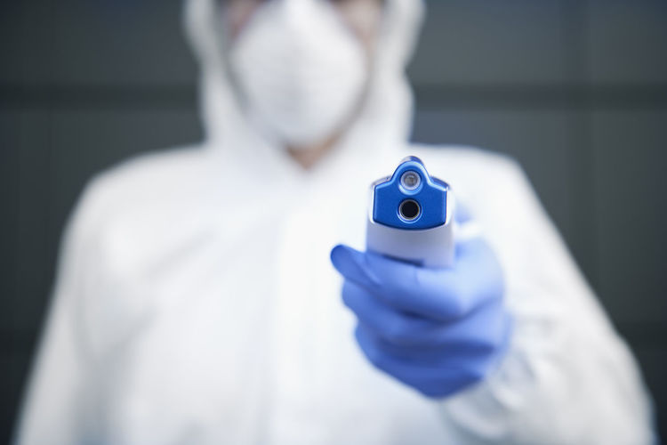 Midsection of doctor holding infrared thermometer