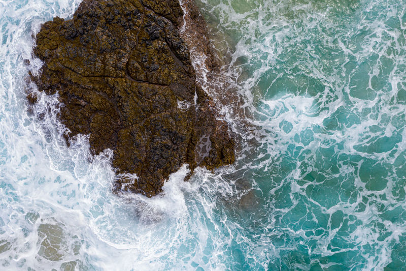 Drone aerial view of waves crashing over rocks on lumaha'i beach on north shore of kauai