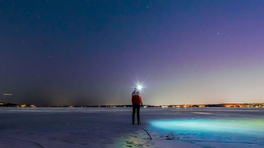 Rear view of woman standing on snow at night