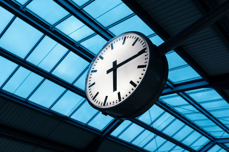 Public indoor clock and skyroof in train station at twilight, clock show time at rush hour