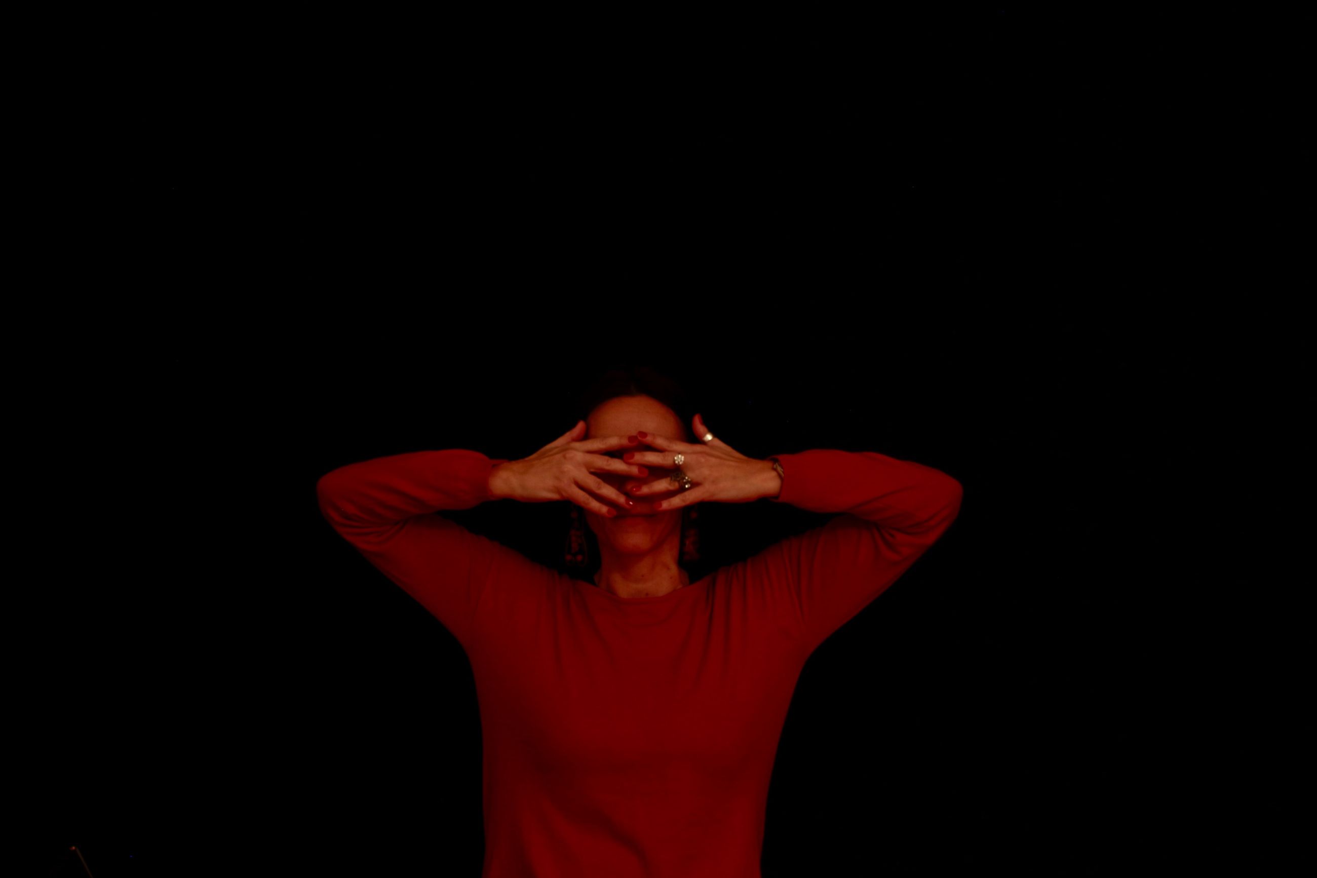 black background, studio shot, one person, indoors, front view, copy space, red, standing, waist up, casual clothing, young adult, cut out, emotion, adult, lifestyles, obscured face, hand, sadness, women, human arm, arms raised, depression - sadness, hairstyle