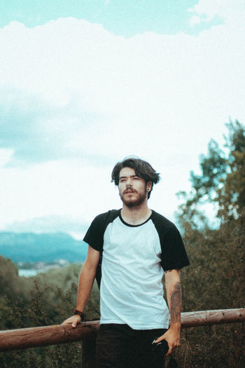 Portrait of young man standing on mountain against sky