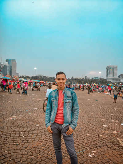 Portrait of young man standing against sky