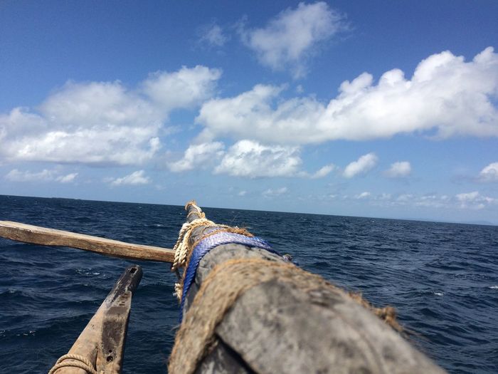Cropped image of outrigger canoe sailing in sea against sky
