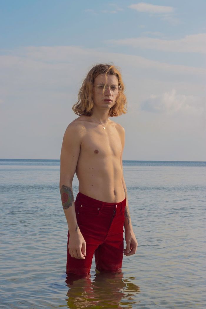 PORTRAIT OF SHIRTLESS MAN STANDING IN SEA
