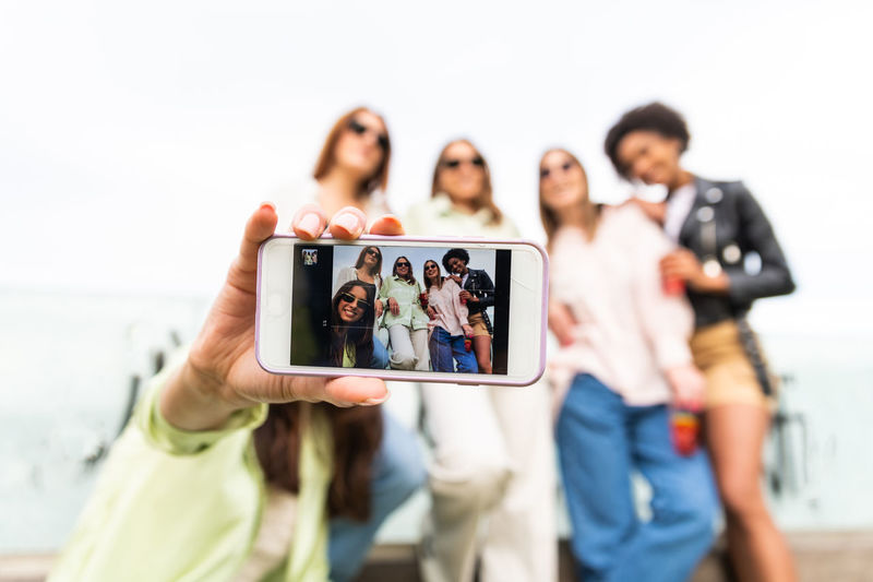 Happy group of women with sunglass, taking selfie with smartphone in sunny day. friendship concept.