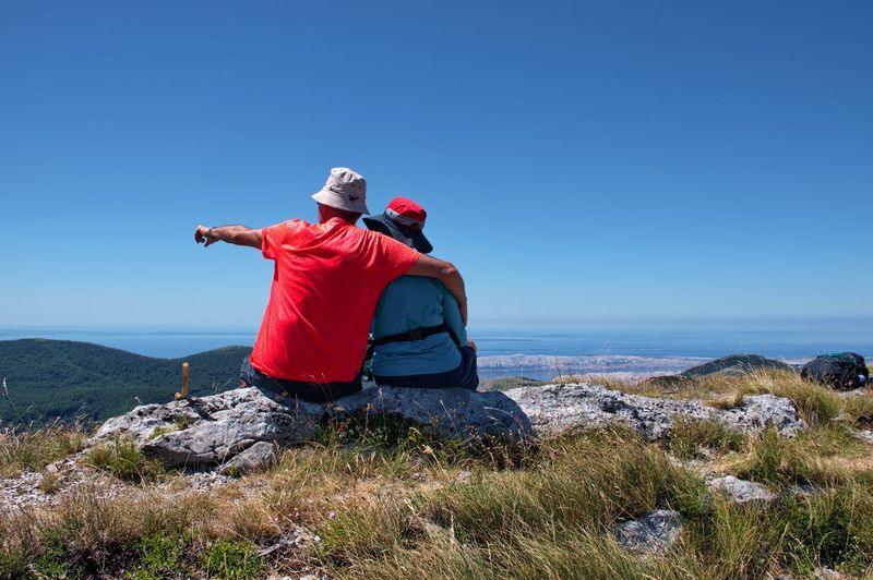 Senior couple siting on mountain top with beautiful view - velebit mountain, croatia