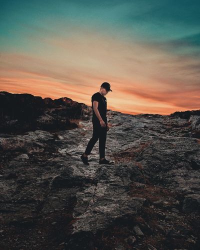 Full length of man standing on rock during sunset