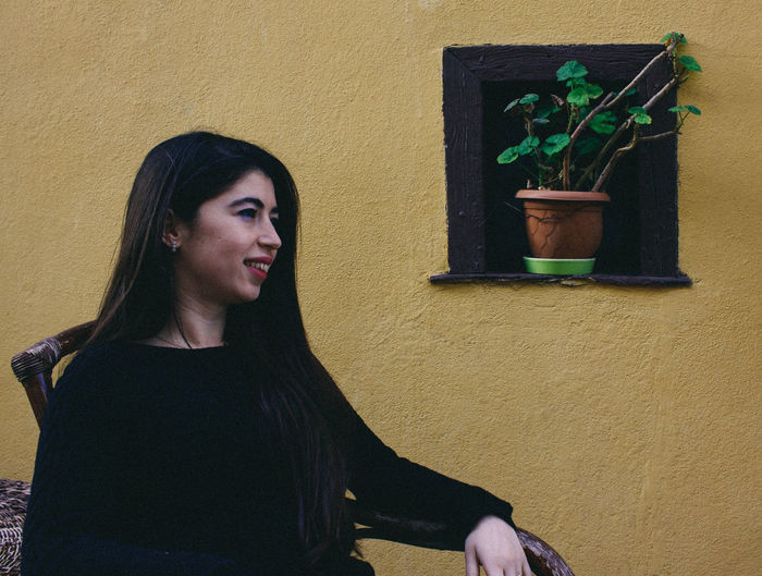 Portrait of young woman against wall