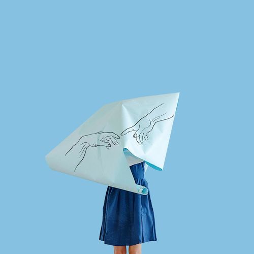 Low angle view of person holding paper against blue background