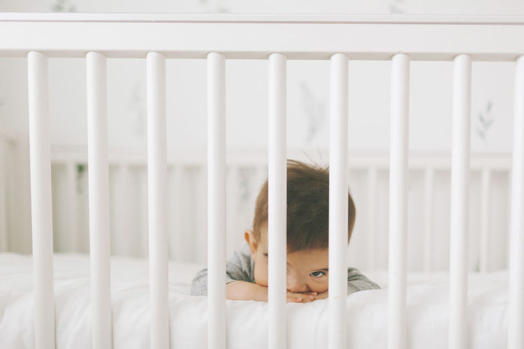 Portrait of cute baby boy lying in crib at home