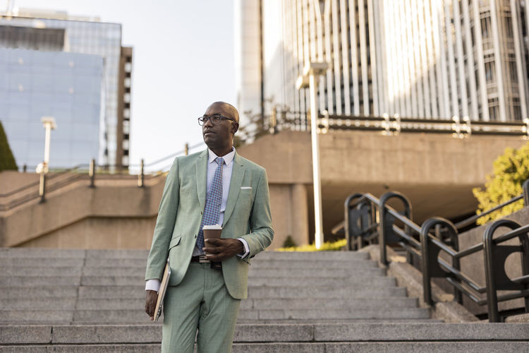 Mature businessman with laptop and coffee cup on steps
