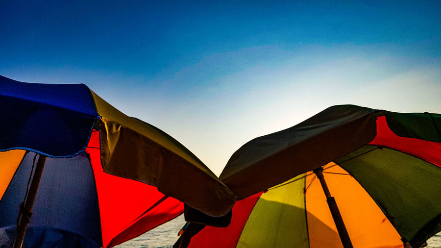 Low angle view of multi colored umbrellas against clear sky