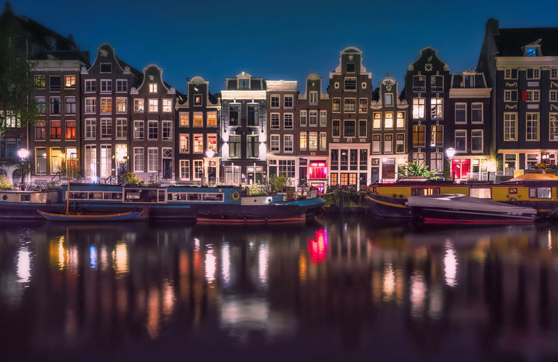 River by illuminated buildings against sky at night