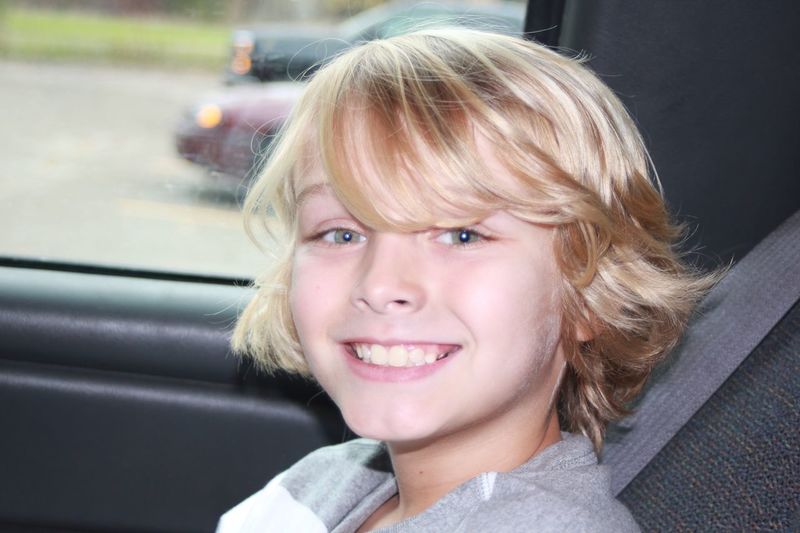 Portrait of blonde boy in car