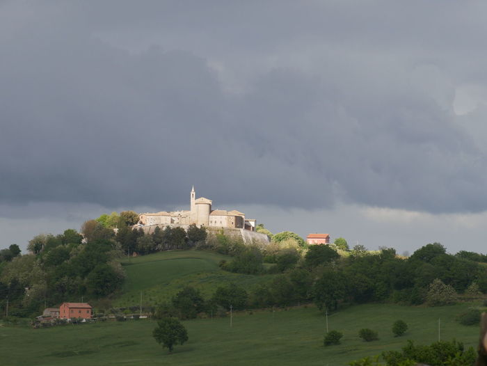 Building on field against cloudy sky