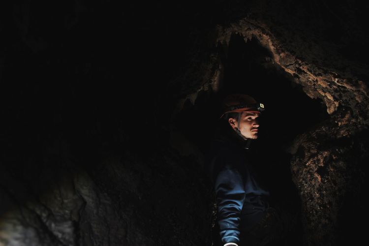 Side view of young man standing in cave