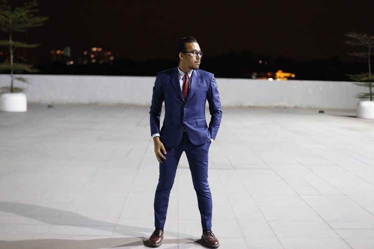 Full length of businessman standing on paved footpath at night