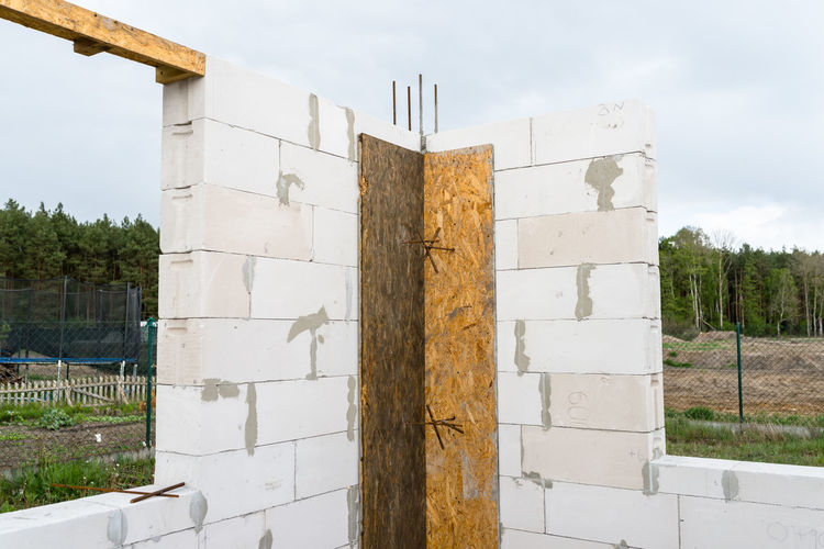 The walls of a house built of white brick with reinforced concrete pillars at the end of which