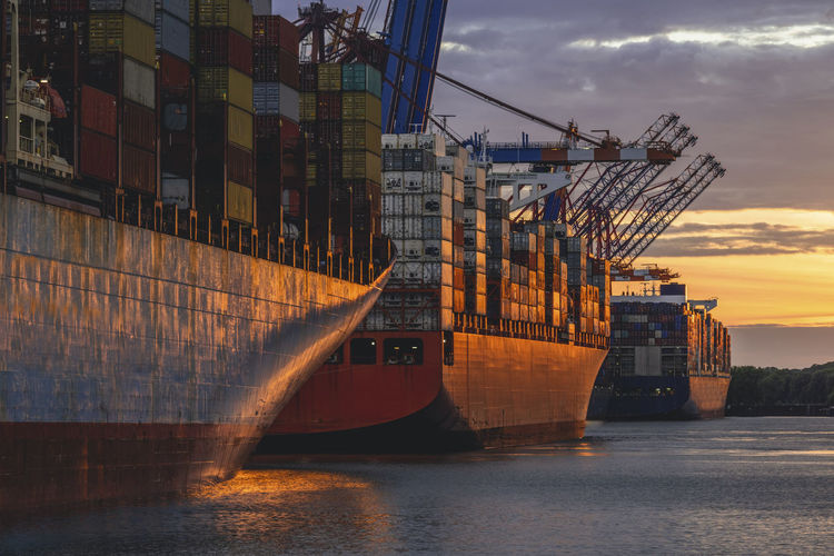 Germany, hamburg, container ships in port of hamburg at dusk