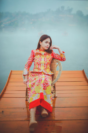 Portrait of young woman sitting on pier