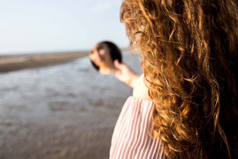 Woman holding hand mirror at beach