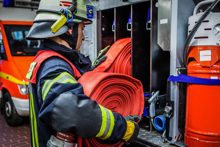 Firefighter arranging hose in rack at fire station