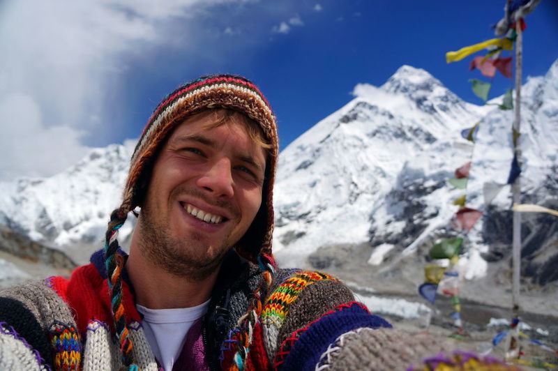 Portrait of young woman standing against snowcapped mountain
