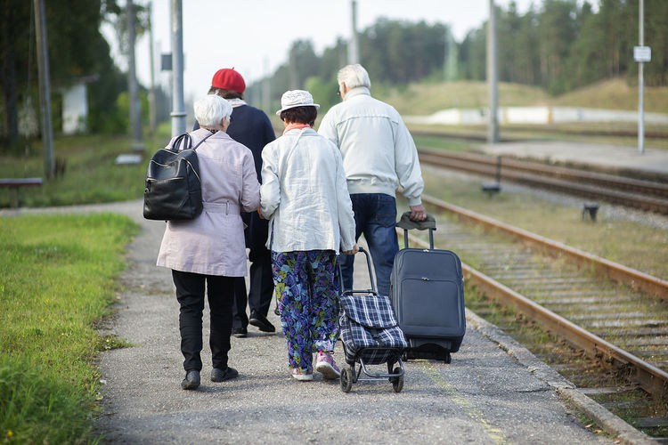 Rear view of a group of seniors elderly old people with luggage waiting for a train to travel