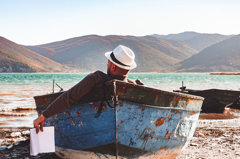 Man in boat at beach against sky