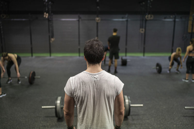 Man standing with athletes exercising in background in gym