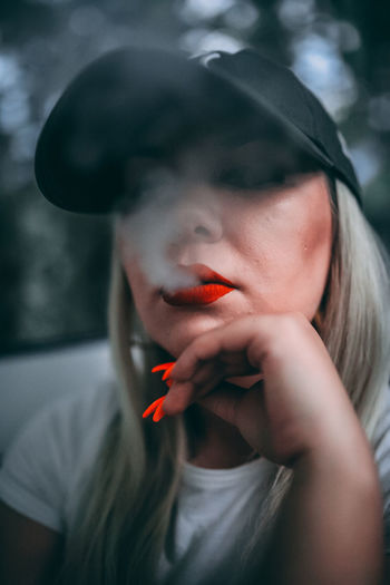 Portrait of young woman smoking outdoors