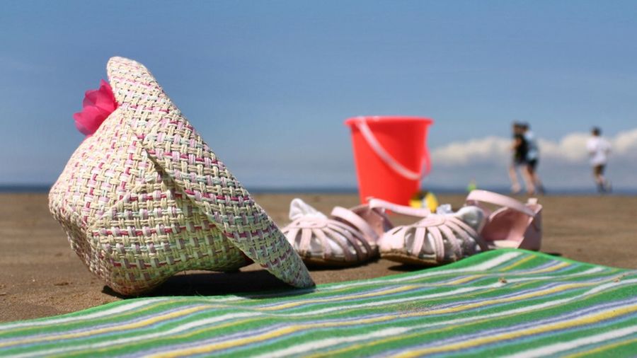 Beach mat with hat and sandal on sand