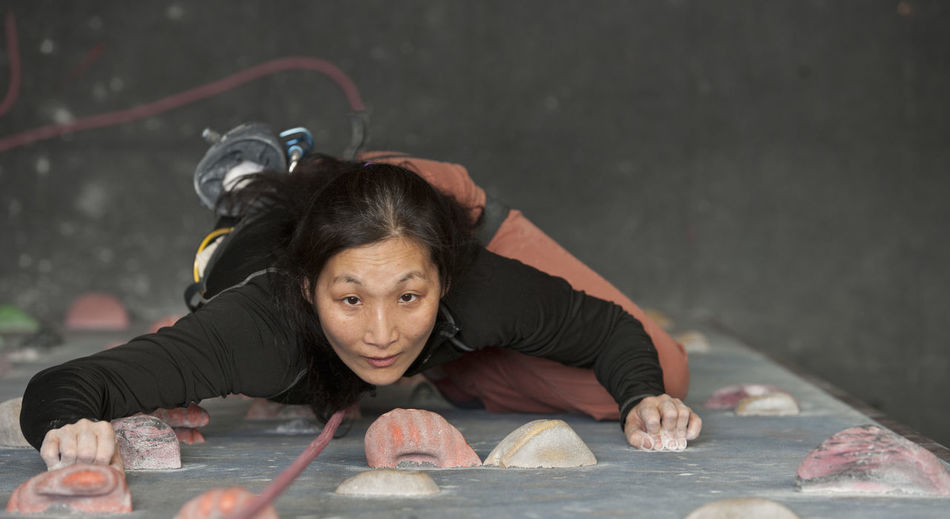 Mature woman climbing at indoor climbing wall in england / uk
