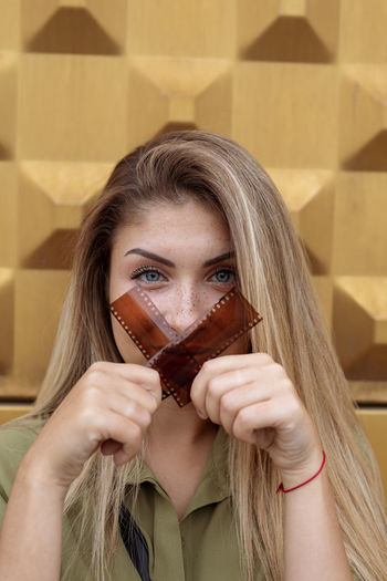 Portrait of beautiful young woman holding film reels