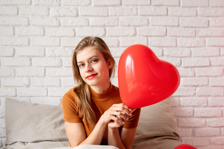 Portrait of young woman holding heart shape balloon