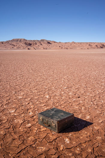 Old leather suitcase in the barren and rocky desert on sunny day