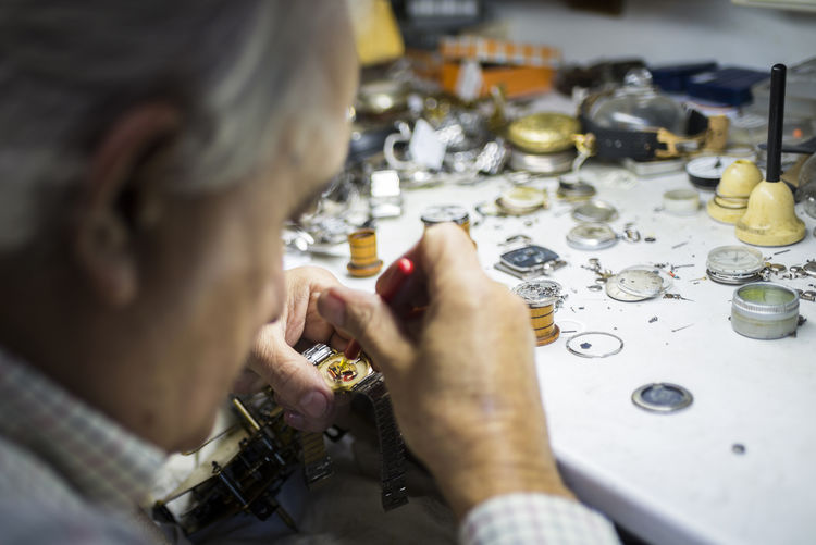 Watchmaker in foreground while working with a wristwatch