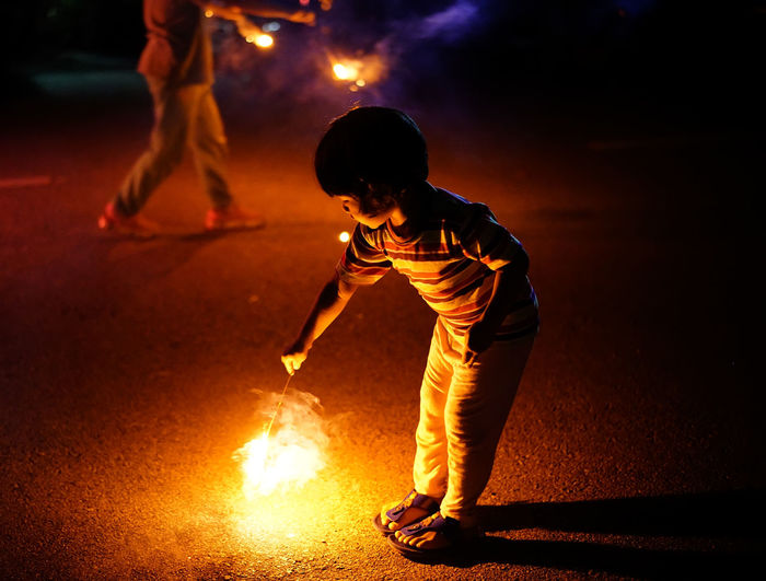Girl holding illuminated firework at night
