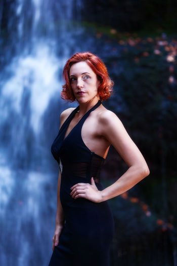 Woman standing against waterfall