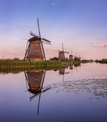 Traditional windmills by lake against sky