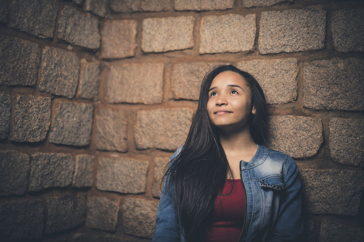 Teenager standing against brick wall