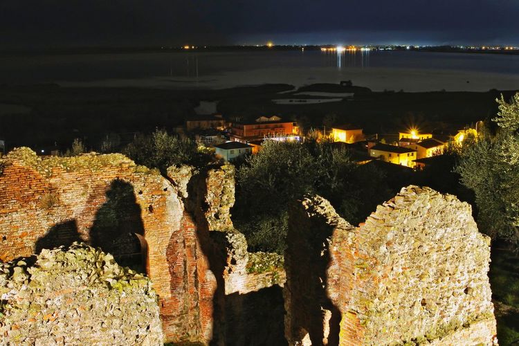 High angle view of illuminated rocks by sea against sky at night