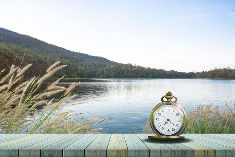 Clock by lake against clear sky