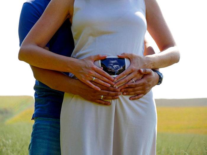 Midsection of couple holding ultrasound while standing on land