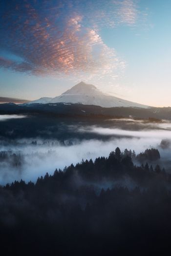 Scenic view of mountains against cloudy sky during sunset
