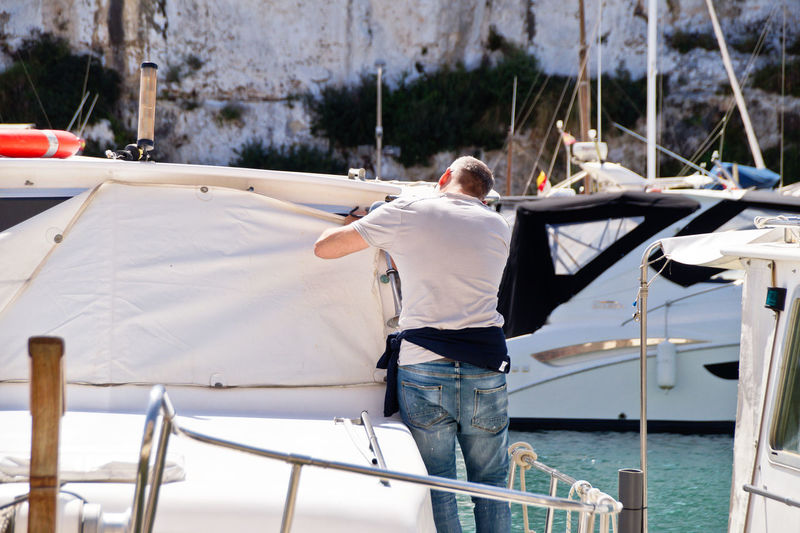 Rear view of man working on sailboat