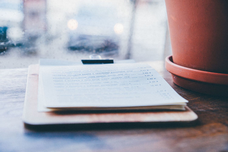 Clipboard with pages on table against window